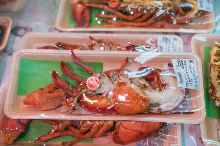 Osaka, Japan - 3 Mar 2018; Japanese local fresh foods; sea food, fish, sashimi, fruits, stawberrry, puffer, salmon, dried food, crab, etc, tourists walking and eating at Kuromon Ichiba Market (fish market)のeditorial素材