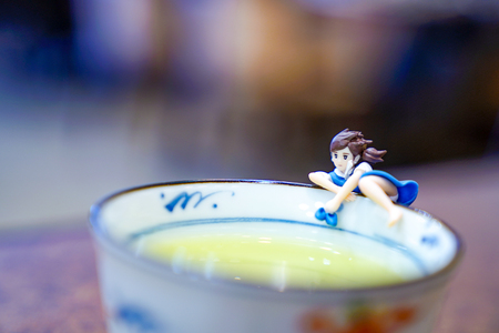 little high school in uniform hang on to rim of tea cupの写真素材