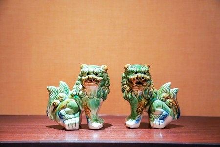 twin green seramic lion stand in the middle of frame with tungsten light.の写真素材