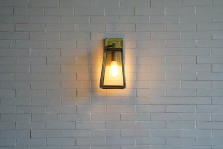 Square steel lamp tungsten/warm light on the white brick wall.