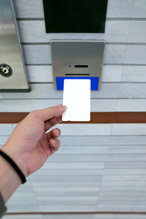 securing lift or elevator access control, man's hand is holding a key card lay up to insert in card hold for unlocking elevator doors before up or down.の写真素材