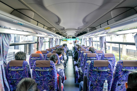 People on the bus were sitting listen to tour guide who standing at front of rowの写真素材