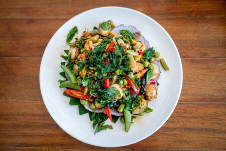 a Thai food Seafood fried in a spicy sauce in white circle dish on wooden table background.の写真素材