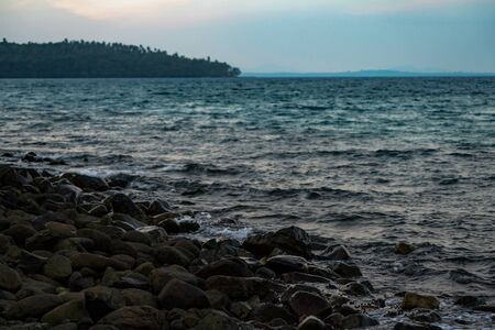 Black dark stone on the beach in the sea with a little snails all that area. It's twiligt time in Asian, Thailand.の写真素材