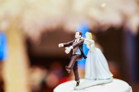 groom doll and statue is running away but bride can catch him finally. the funny wedding story doll on the top of cake.の写真素材