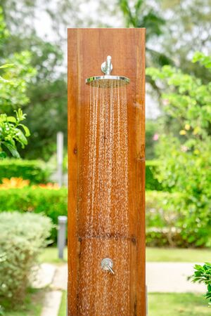 Outdoor shower head stick on the wooden plate pole design for showering body before jumping in the resort pool.の写真素材