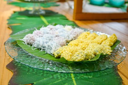 Thailand vintage dessert call mung bean rice-crepe with mung bean and coconut slide on top arranged on banana leaf in glass dish on wood table in the garden.の写真素材
