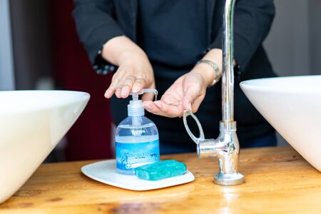 Business woman in dark black suit is puhsing washing soap on her hand beside the sink.の写真素材