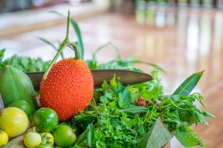 Various local Thai herbs in the basket such as Gac fruit, lime, basil, etc. all of this is an...