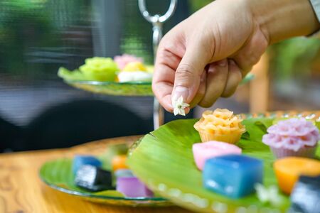 Thai Chef's hand is decorating Varieties traditional colorful Thai desserts set; steaming flour,...