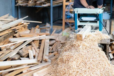 Professional Asian woodworker is preparing and planing wood plate by planer machine for hand crafting the home office furniture and wood wall partition.の写真素材