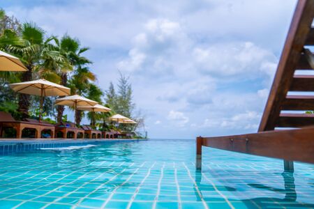 Outdoor swimming pool and Wood bed - chair in the pool with open sky.の写真素材