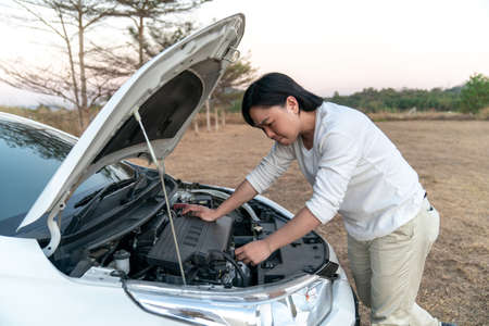 Asian man is stressed with the broblem car and try to fix it by himself in the large field forest...