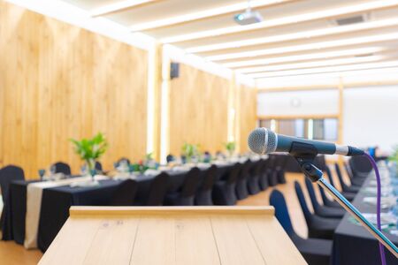 Close up to microphone beside the podium with blur long black table dinner time in tungsten warm...