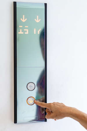 Asian old woman hand points to the button of elevator.