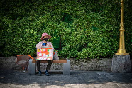 Bangkok, Thailand - 26 Jul 2020, Lottery seller sit on the chair inside tree shade and waits for customer to buy her Lottery at 3 p.m., Bangkok, Thailand.のeditorial素材