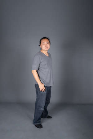 Asian long hair friendly and positive man is posting and standing in front of gray background with studio light.の写真素材