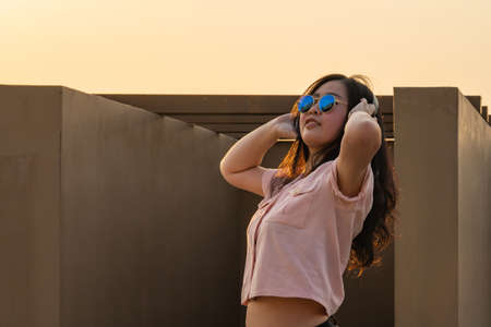 Asian glasses long hair girl is dancing on the rooftop of the building in twilight sunset time.の写真素材