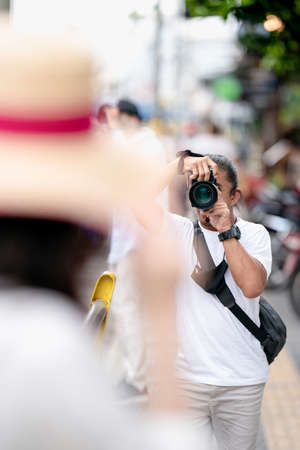 Professional Asian Camera man focus on the image with his mirrorless camera beside the street outdoor field.の写真素材