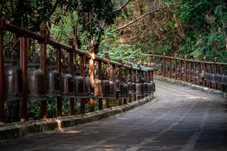 Walkway with the metal bronze bells around and beside of it in the jungle environment, at Wat Phra That Doi Tung temple, Chiang Rai Province, North of Thailand.の写真素材