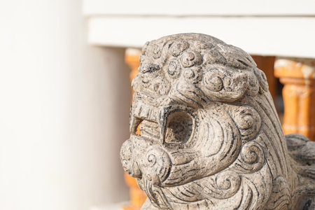 Asian white stone lion statue Chinese vintage style in front of temple on the blur background.
