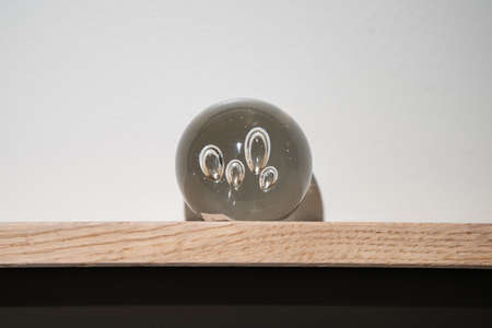 Crystal transparency ball abstract object decoration, lay on a wood shelf in the living room.
