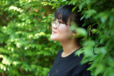 Portrait of the Asian glassese Thai woman is standing in the garden in the morning.の写真素材