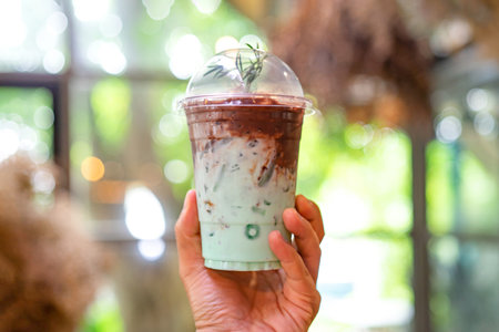 Chocolate milk and mint flavor in plastic cup for take away on green tree bokeh background.の写真素材
