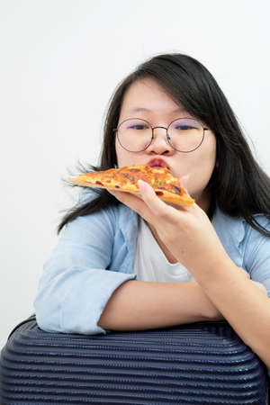 Happy glasses Asian young woman eat Pizza on white background.の写真素材