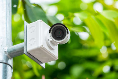 CCTV camera is installed in the garden with blur green tree background for monitor and safety system...