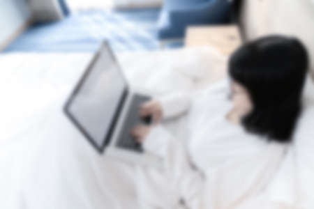 Blur Topview of Glasses Asian cute woman works with laptop white screen on the bed in Work From Home...