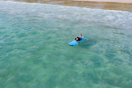 Drone view of Asian Surf board man plays surf in the sea beach at Kata Beach, Phuket Thailand.