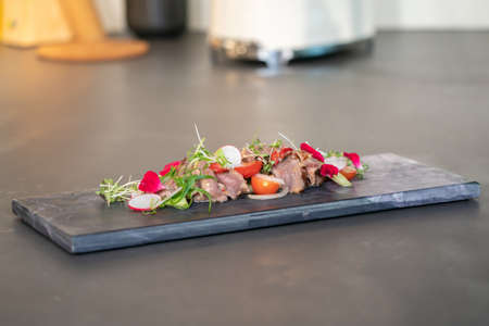 Spicy Thai Beef Salad garnished on top with cress and micro herb was put on a rectangular stone plate.の写真素材