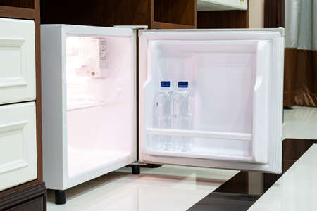 Refrigerator fridge mini size under the table counter with wooden desk beside it in hotel delux room.の写真素材