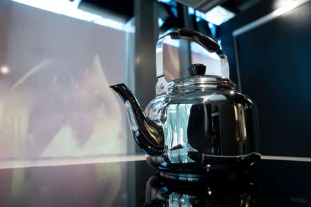Stainless Water Crow or Vintage Kettle tea pot on electronic stove in modern dark blue background.の写真素材