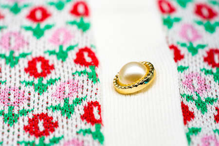 Close up to knitting flower pink and red sweater pearl gold circle buttons on the top of tshirt sweater.の写真素材