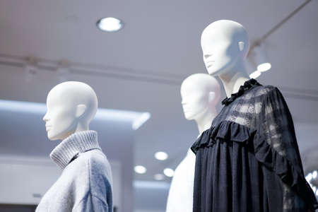Female mannequins are dressed in casual clothes with a red-orange theme in fashion shop at the...