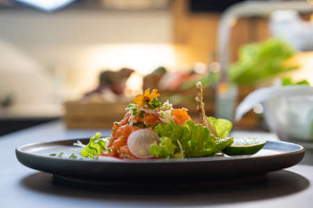 Close up Spicy Raw Salmon Salad Thai food style decorated with Crispy fried fish skin and Yellow Flower on top and micro herb around dish. Ready to serve and eat.の写真素材