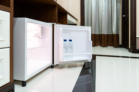 Refrigerator fridge mini size under the table counter with wooden desk beside it in hotel delux room.の写真素材