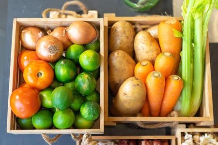 FlatLay Tabletop - Group of vegetable Carrot, Potato, Lime, Tomato, Onion in wood box. It's shot in studio light.の写真素材
