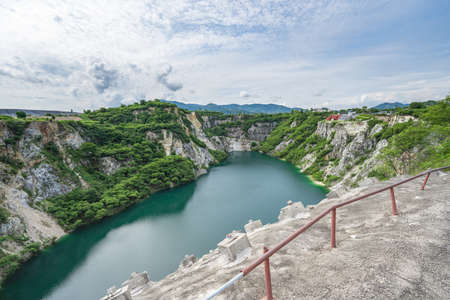 The water in the pond is emerald green surrounded by limestone mountains, big trees and clear sky in Grand Canyon Chonburi, Thailand.の写真素材