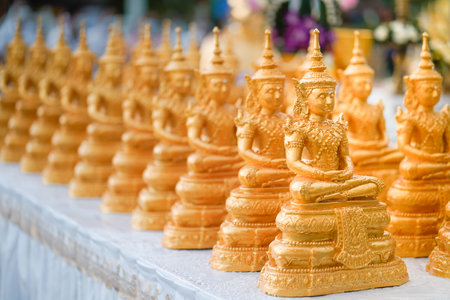 Golden Buddha statues placed on the white table, which were wet by rain felled and prepared for a religion ceremony event.の写真素材