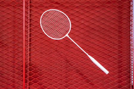 one badminton racket is hung on red grill by a cable tie for display in exhibition sports event