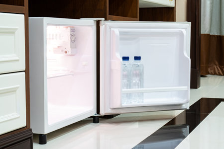 Refrigerator fridge mini size under the table counter with wooden desk beside it in hotel delux room.の写真素材