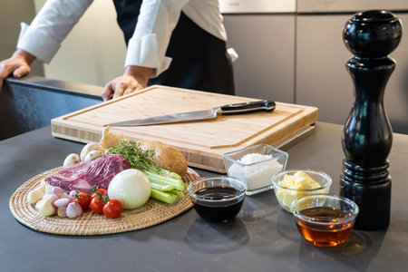 Environment on counter kitchen, prepared Onion, Beef, Sauce and food ingredients for Steak Cooking with standing professional chef background behind it.の写真素材