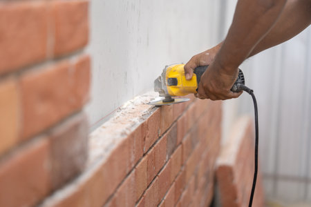 Close up worker holds Hand-Hold Sawing Machine and cuts brick foam plate board for wall installation.の写真素材