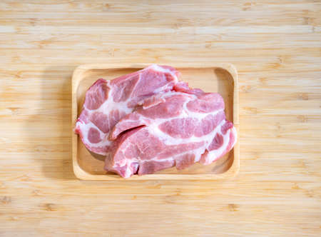 Flatlay Topview Raw Pork is prepared for Cook, It is on wood plate in studio light with Chef hand background. Clipping Paths.の写真素材
