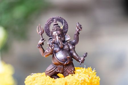 Small replica of Ganesh with iron color is worshiped with a glowing yellow marigold.の写真素材