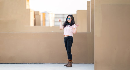 Very Cute Smiling Asian Teenager Female stands and poses finger point to opposite two ways in sunset...