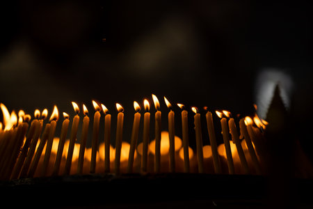 lighted candles laid out in circle in the dark with small white shadow on the right side of the background.の写真素材